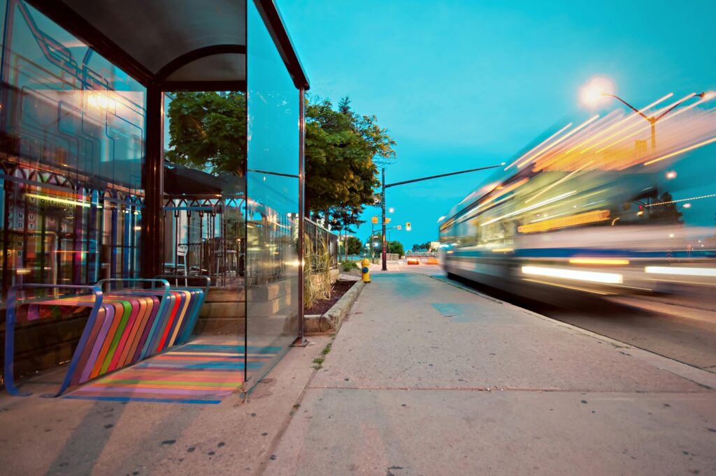 pexels photo 136739 136739 1 Colorful city bus stop with vibrant benches, blurred motion of a passing bus at dusk.